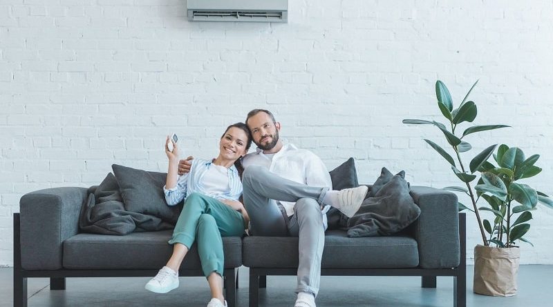 Couple Sitting On a Gray Sofa Underneath a Central Air Conditioning Unit