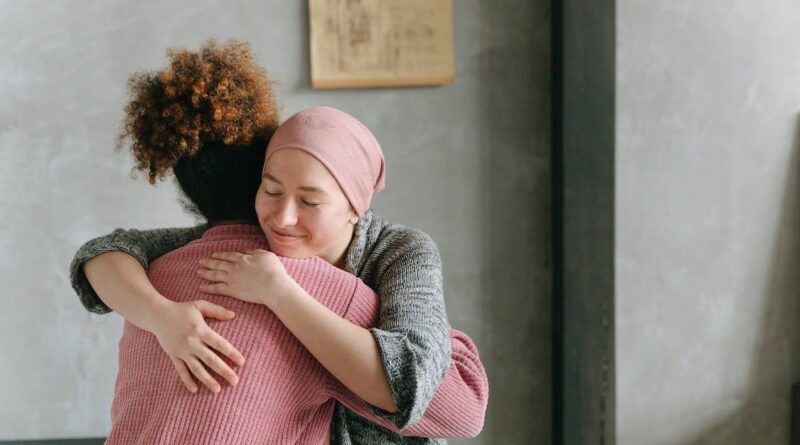 6 Tips to Support a Loved One with Chronic Disease / Two women, one in pink and the other in grey with her head wrapped hugging each other
