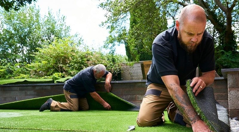 Men laying down artificial grass