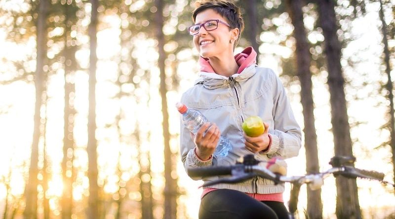 Woman with Short Hair and Glasse on a bike with a bottle of water and an apple