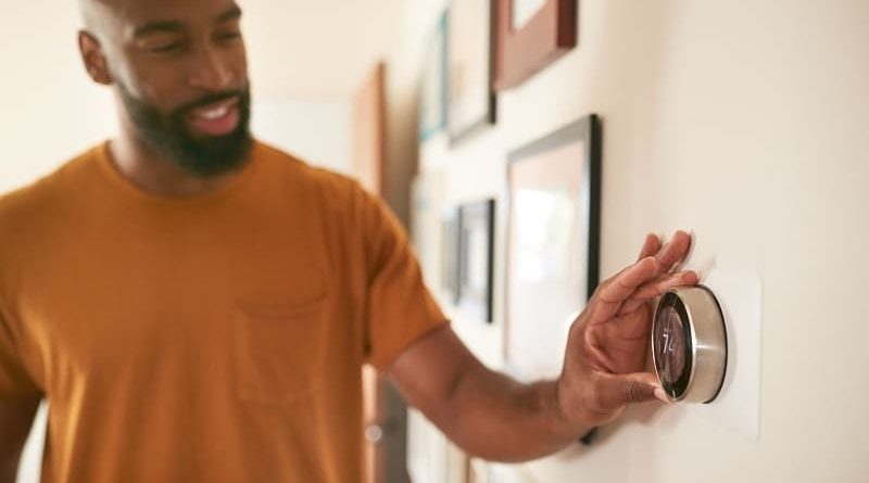 Home Heating Tips / Man adjusting his home thermostat