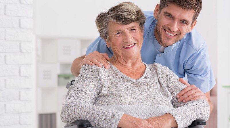 Tips for Families on How to Care for Grandparents / Smiling Young Man with His Grandmother Who is in a Wheelchair