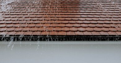Rain pouring off of a roof / The Importance of Timely Roof Repairs: