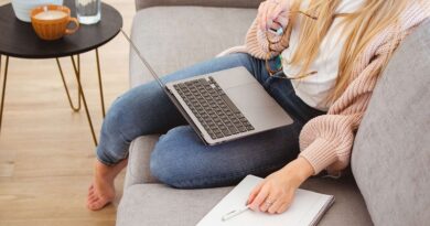 Woman sitting on her sofa with a laptop on her lap