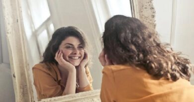 Smiling Woman Looking Into a Mirror / 7 Dental Procedures You Can Consider to Achieve a Beautiful Smile