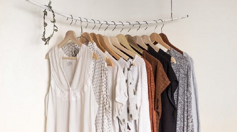 Clothes on wooden hangers on a white pole hanging from the ceiling / Tips To Fall In Love With Your Closet Again