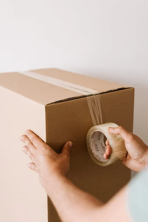 A person taping a moving box shut