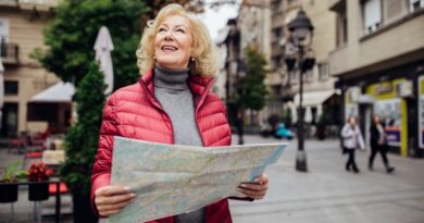 Middle Aged Woman in Red Puffer Jacket Holding a Map and Smiling