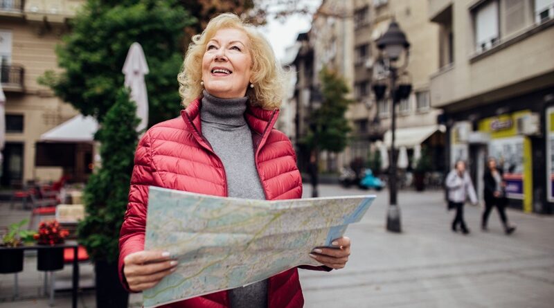Middle Aged Woman in Red Puffer Jacket Holding a Map and Smiling