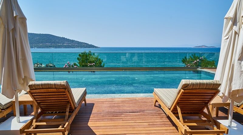 Sun loungers on teak deck overlooking an infinity pool and the ocean / Europe's Finest Resorts: A Journey Through Luxury and Splendor