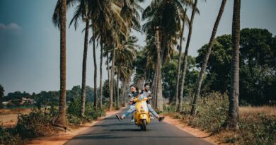 Couple riding on a yellow scooter on a palm tree lined road / Four Essential International Travel Must-Haves