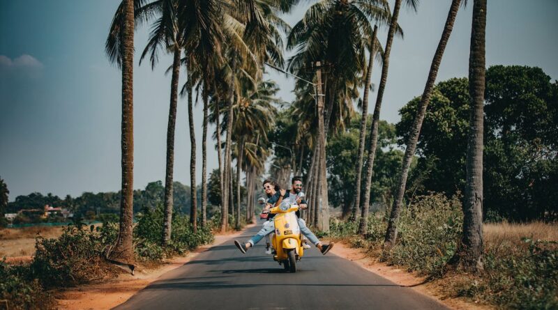 Couple riding on a yellow scooter on a palm tree lined road / Four Essential International Travel Must-Haves