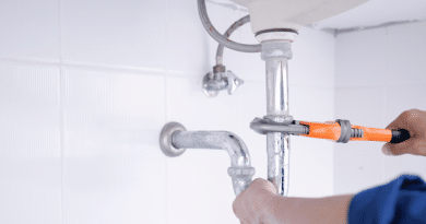 Plumber Working On a Pipe with an Orange Handled Wrench / Choosing the Right Plumbing Service: Factors to Consider