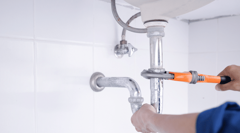 Plumber Working On a Pipe with an Orange Handled Wrench / Choosing the Right Plumbing Service: Factors to Consider