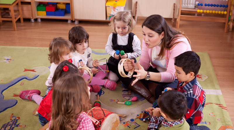 Teacher and Preschoolers on rug in classroom with musical instruments / Preschool & The Many Benefits That If Offers Australia’s Kids Today And Always.