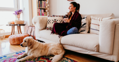 Woman sitting on her sofa with a mug in her hand and a dog on a rug. / The Essentials for Making a Relaxing Space Inside or Outside Your Home