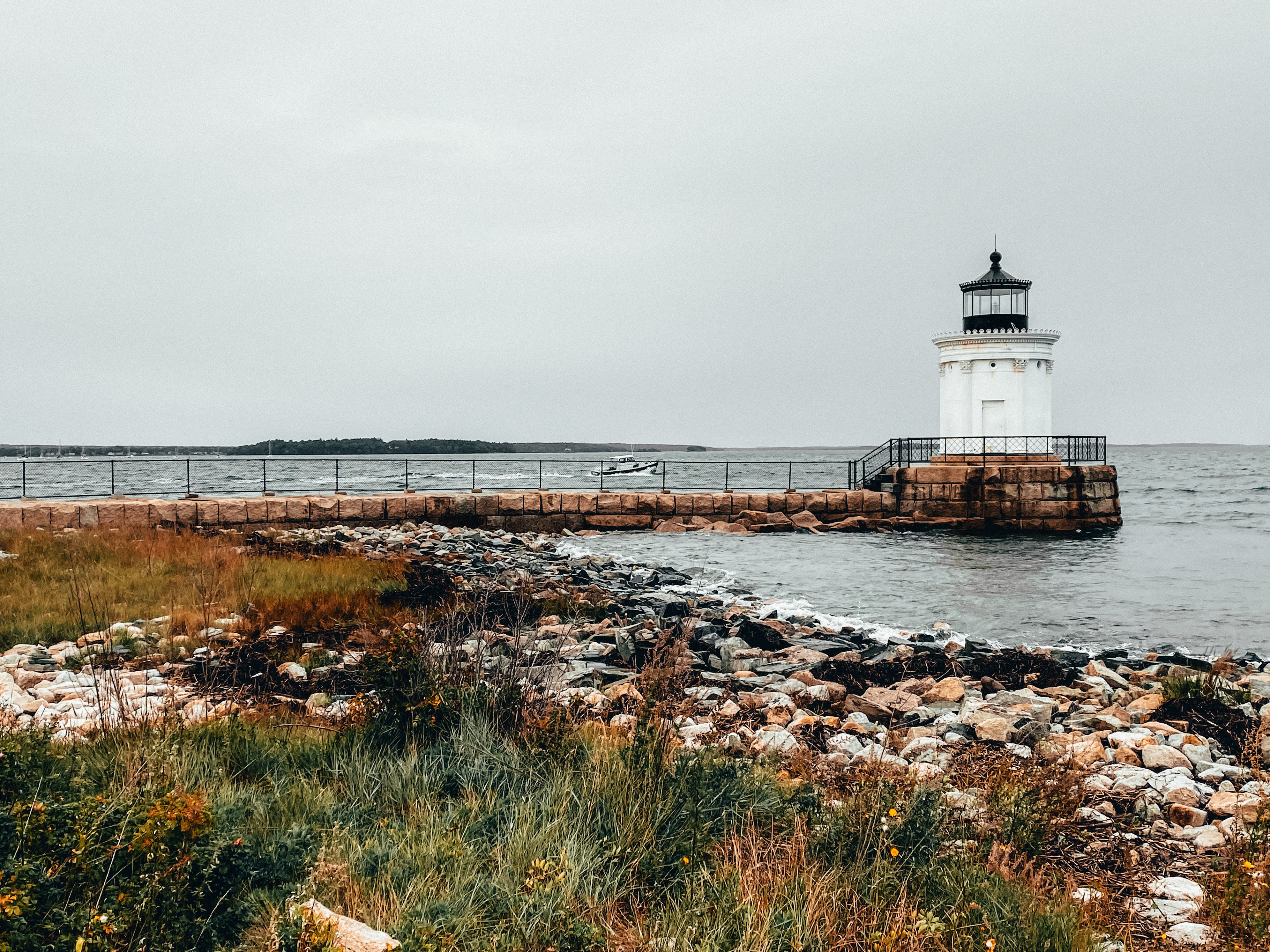 Small Lighthouse at the end of a Stone Walkway on the Coast of Portland Maine