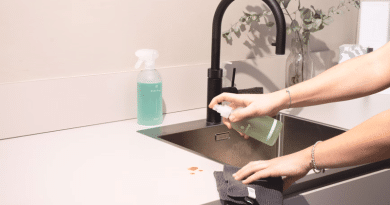 Woman Spraying Kitchen Counter / Important Home Maintenance Tasks to Tackle Sooner Rather Than Later