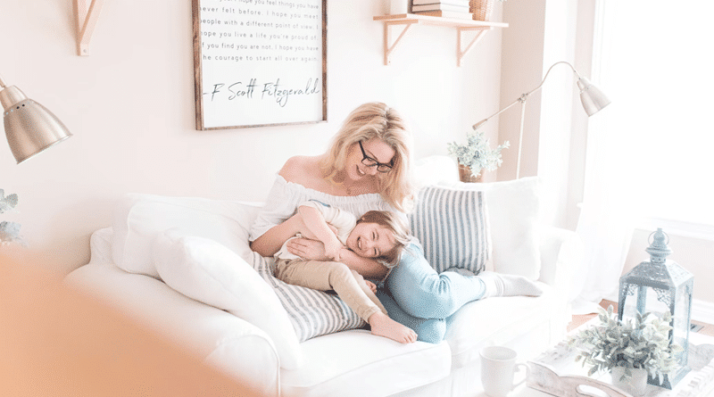 Woman snuggling with a young child on a white sofa with blue stiped pillows / How To Make Your Home A Happier, Healthier Place