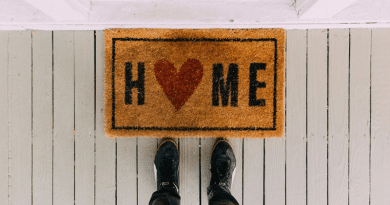 Person standing by a welcome mat at the front door of a home / Things to Update in Your Home That Can Make a Big Difference