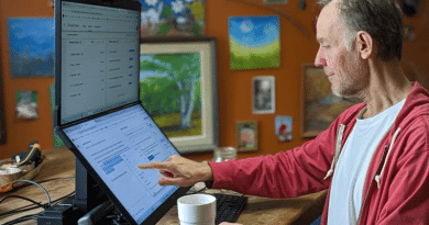 Man using a touchscreen computer with a stacked monitor.